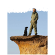 Eine Person in einem grünen Overall steht auf einem felsigen Vorsprung mit einem schwarzen Hund neben sich, vor einem klaren blauen Himmel.
