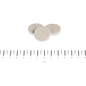 Drei beigefarbene, mit Bruchrille versehene Tiertabletten über einem Zentimeterlineal, das mit Zahlen und „cm“ markiert ist.