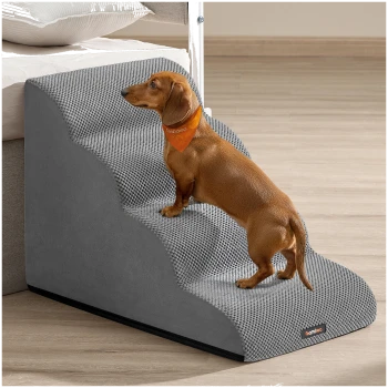 Brauner Dackel mit orangefarbener Bandana klettert graue strukturierte Haustiertreppe neben einem Bett hinauf.