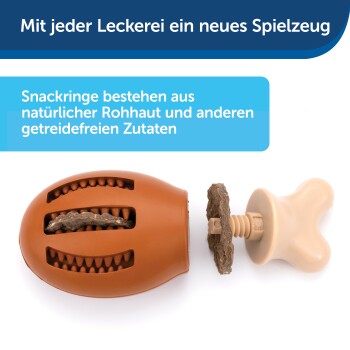 Braunes, strukturiertes Hundespielzeug mit einem Knochenanhänger und Leckerli darin. Text: "Jede Leckerei ist ein neues Spielzeug" und "Snackringe aus natürlichem Rohhaut."