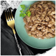 Gros plan sur une assiette verte remplie de nourriture pour animaux humide et déchiquetée, garnie d'une branche de persil, à côté d'une fourchette dorée sur un tissu sombre.