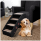 Eine schwarze Haustiertreppe mit beigen Stufen, mit Pfotenabdruckdesigns, neben einem flauschigen Hund, der auf einem gewebten Teppich in einem gemütlichen Wohnzimmer sitzt.
