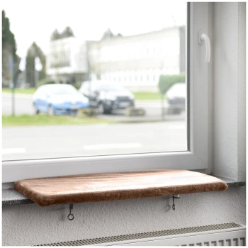 Eine gemütliche Katzenfensterbank mit einem weichen, braunen Kissen, montiert auf einer Fensterbank, mit Blick auf eine Straße mit geparkten Autos.
