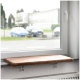Eine gemütliche Katzenfensterbank mit einem weichen, braunen Kissen, montiert auf einer Fensterbank, mit Blick auf eine Straße mit geparkten Autos.