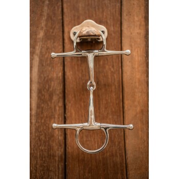 Ein glänzendes Metallpferdegebiss, das an einer Holzwand montiert ist und sein glattes Design und Handwerk zeigt.