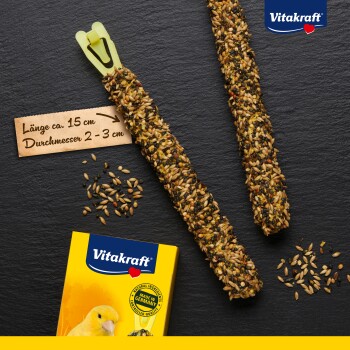 Dwa patyczki nasienne dla ptaków, o długości około 15 cm i szerokości 2-3 cm, w żółtym opakowaniu oznaczonym "Vitakraft" i z wizerunkiem kanarka.