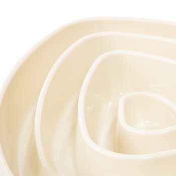 Eine Nahaufnahme einer beigen, spiralförmigen Haustierfutterschüssel mit mehreren ineinander geschachtelten Schichten, die für langsames Füttern konzipiert ist.