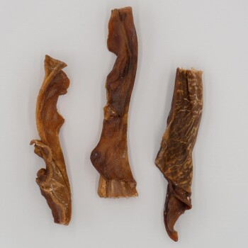 Drei gedrehte, getrocknete Fleischkauartikel für Hunde, vor einem weißen Hintergrund präsentiert.