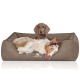 Ein gemütliches braunes Hundebett mit "KNUFFELWUFFF"-Logo, mit einem entspannten Australian Shepherd und einem anderen Hund, der sich ausruht.