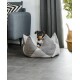 Ein kleiner Hund ruht in einem stilvollen, grauen Haustierbett in Form eines Berges, mit einem modernen Wohnzimmer im Hintergrund.