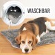 Ein Beagle ruht auf einem grauen Haustierbett, im Hintergrund eine Waschmaschine mit einer abnehmbaren Decke, die mit "WASCHBAR" beschriftet ist.