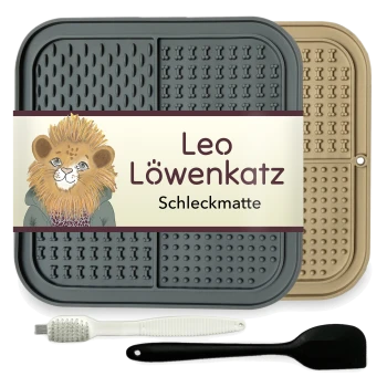Eine Futtermatte für Haustiere mit der Aufschrift "Leo Löwenkatz Schleckmatte" mit einem Löwendesign, grauen und beigen Farben, plus einer weißen Bürste und einem schwarzen Spatel.