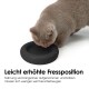 Eine hellgraue Katze frisst aus einer schwarzen erhöhten Schüssel. Der deutsche Text erklärt, dass es langsameres Fressen und weniger Bücken für Katzen fördert.