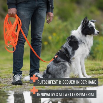 Person hält eine lange orange Leine mit einem schwarz-weißen Hund; deutscher Text über rutschfesten Griff und wetterfestes Material.