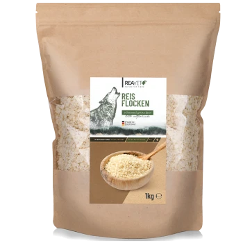 Ein 1-kg-Beutel REAVET Reisflocken für Haustiere, mit einer Wolfsgrafik, mit dem Text "Reis Flocken" und "schonend getrocknet" in Grün.