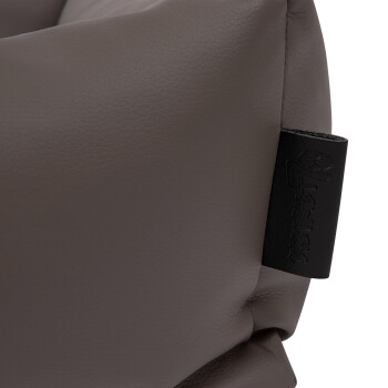 Nahaufnahme eines weichen, braunen Haustierbettes mit strukturierter Oberfläche und einem schwarzen Etikett, das den Markennamen geprägt hat.