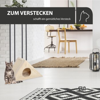Eine verspielte graue Tabby sitzt neben einem beigen dreieckigen Katzenversteck in einem modernen Wohnraum. Text: "ZUM VERSTECKEN schafft ein gemütliches Versteck."