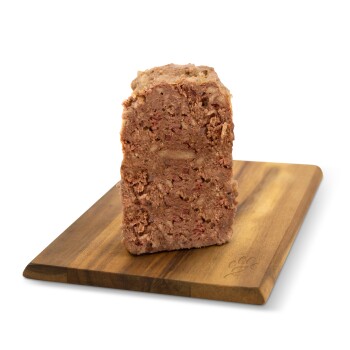 Eine Scheibe Haustierfutterlaib, die auf einem Holzschneidebrett präsentiert wird, mit ihrer strukturierten Oberfläche und fleischiger Farbe.