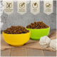 Zwei Schalen mit braunem Hundefutter, eine gelbe und eine grüne, mit weißen Seilspielzeugen. Text: "Getreidefrei", "Hoher Proteingehalt", "Fettarm", "Vitamine A, E, D3."