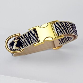 Ein stilvolles Haustierhalsband mit einem navy- und cremefarbenen Streifenmuster, einer glänzenden goldenen Schnalle und einem dekorativen Quastenanhänger.