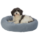 Ein flauschiger schwarz-weißer Hund, der auf einem weichen, runden, grauen Haustierbett entspannt.