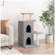 Graue Katzenbaum mit zwei Ebenen, zwei Verstecken und Kratzpfosten, neben einem beigen Sofa und einer Topfpflanze platziert.