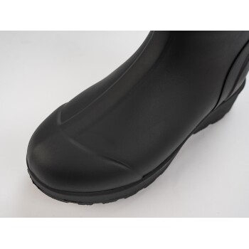 Nahaufnahme eines schwarzen Gummistiefels, der seine glatte Textur und die abgerundete Zehe zeigt, vor einem weißen Hintergrund.