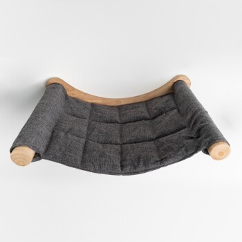 Eine graue Haustierhängematte mit einer gepolsterten Stoffoberfläche, unterstützt von gebogenen Holzrahmen, vor einem weißen Hintergrund präsentiert.