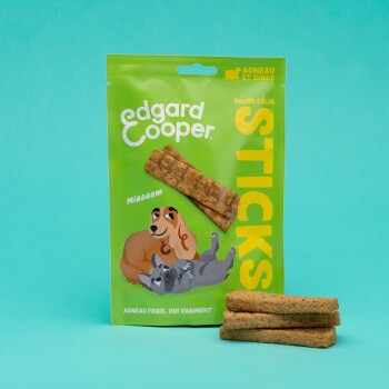 Emballage de friandises pour chiens Edgard Cooper vert étiqueté "STICKS", présentant un chien et un chat de dessin animé avec "Miaaaam" et "Agneau frais, oui vraiment."