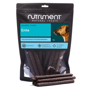 Nutriment Natural Treats Gourmet-Sticks ‚Ente‘ 1 kg Tüte mit dunklen Enten-Kaustangen für Hunde, einige davon vorne gestapelt.
