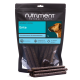 Nutriment Natural Treats Gourmet-Sticks ‚Ente‘ 1 kg Tüte mit dunklen Enten-Kaustangen für Hunde, einige davon vorne gestapelt.