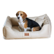 Beagle sitzt in beigem Leder-Haustierbett mit Kissen, vorne beschriftet mit „tierland.de“.