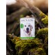 Eine Dose "DOG'S LOVE" Hundefutter mit einem lächelnden Labrador-Label, auf moosigem Holz platziert, mit Text und Zutaten wie Kartoffeln und Pflaumen.