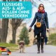 Eine Frau in einer schwarzen Lederjacke und rotem Schal führt einen kleinen braunen Hund in einem Park. Text: "FLÜSSIGES AUS- & AUF-ROLLEN OHNE VERHEDDERN."