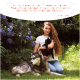 Eine Frau sitzt in einem Garten mit lila Blumen, hält eine schwarze Katze neben einem großen Hund, mit einem Zitat von Lena Huber über Haustierprodukte.