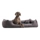 Ein elegantes graues Hundebett mit plüschigem Design, auf dem ein Hund bequem ruht, das seinen weichen Stoff und die unterstützenden Kanten zeigt.