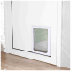 Eine weiße Haustiertür, die in einer weißen Tür installiert ist, mit einer klaren Klappe und einem metallischen Boden, mit sichtbarem Holzboden darunter.