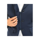 Eine Nahaufnahme einer Hand einer Frau, die den Reißverschluss einer marineblauen Jacke anpasst, mit silbernen Knöpfen und einem weißen Hemd darunter.