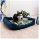 Ein schwarz-weißer Hund ruht auf einem plüschigen, marineblauen Haustierbett mit einem grünen Kissen in einem hellen, modernen Raum.
