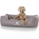 Ein hellgraues Hundebett mit dem Logo "KNUFFELWUFF", das prominent angezeigt wird, mit einem entspannten Hund, der bequem darauf liegt.