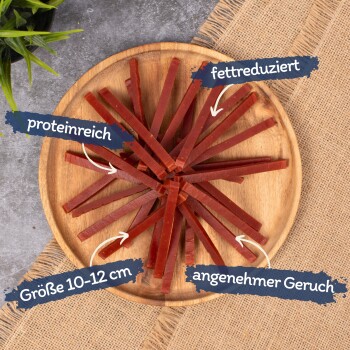 Haustier-Leckerlistreifen in einem kreisförmigen Muster auf einem Holzbrett, beschriftet mit "proteinreich", "fettreduziert", "Größe 10-12 cm" und "angenehmer Geruch."