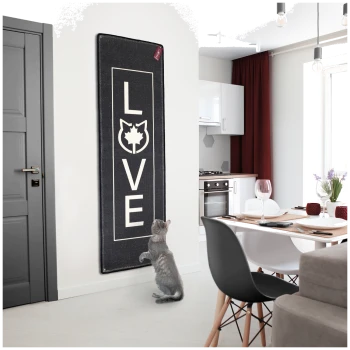 Eine graue Katze steht auf ihren Hinterbeinen neben einer schwarzen Matte mit "LOVE" und einer Katzensilhouette in einer modernen Küche.