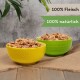 Zwei Schalen mit Haustierfutter, eine gelbe und eine grüne, gefüllt mit Fleisch, beschriftet mit "100% Fleisch" und "100% natürlich" auf einem rustikalen Hintergrund.