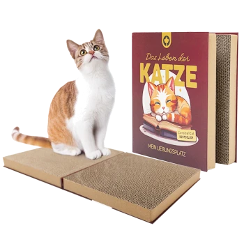 Orange-weiße Katze sitzt auf einem Kartonkratzbrett neben einem buchförmigen Katzenkratzbrett mit der Aufschrift "Das Leben der Katze."