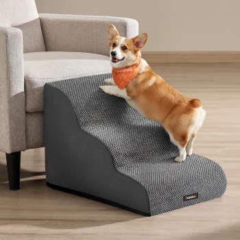 Corgi klettert eine grau strukturierte Haustierrampe zur Couch hinauf, trägt ein oranges Bandana mit weißem Text und einem kleinen schwarzen Produktschild.
