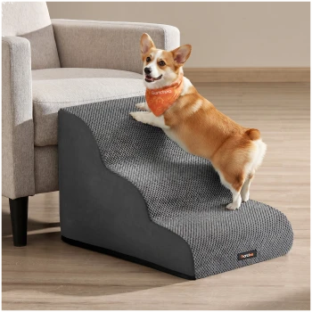 Corgi klettert eine grau strukturierte Haustierrampe zur Couch hinauf, trägt ein oranges Bandana mit weißem Text und einem kleinen schwarzen Produktschild.