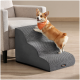 Corgi klettert eine grau strukturierte Haustierrampe zur Couch hinauf, trägt ein oranges Bandana mit weißem Text und einem kleinen schwarzen Produktschild.