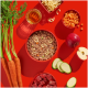 Ein roter Hintergrund zeigt eine Schüssel mit Haustierfutter mit Fleisch, Gemüse und Pasta, umgeben von Karotten, einem Apfel und Gurkenscheiben.