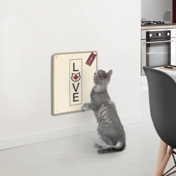 Eine graue Katze steht auf den Hinterbeinen und greift nach einem wandmontierten Kratzbrett, das in fetten Buchstaben "LIEBE" sagt.