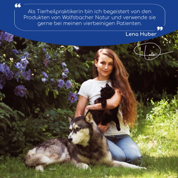 Eine Frau mit langen Haaren hält eine schwarze Katze neben einem großen Hund in einem Garten mit lila Blumen, mit einem Zitat von Lena Huber zu Haustierprodukten.